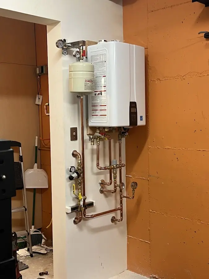 Plumbing technician inspecting water heater connections in Fort Scott